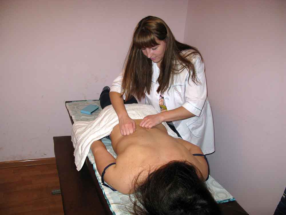 Дівчина масажист вчиться робити масаж. Курси масажу та курси реабілітації у м.Івано-Франківськ